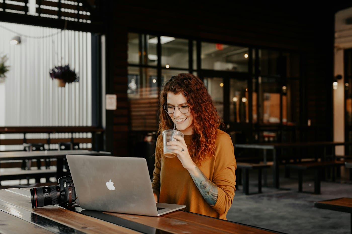 A woman smiling at her laptop in a café
